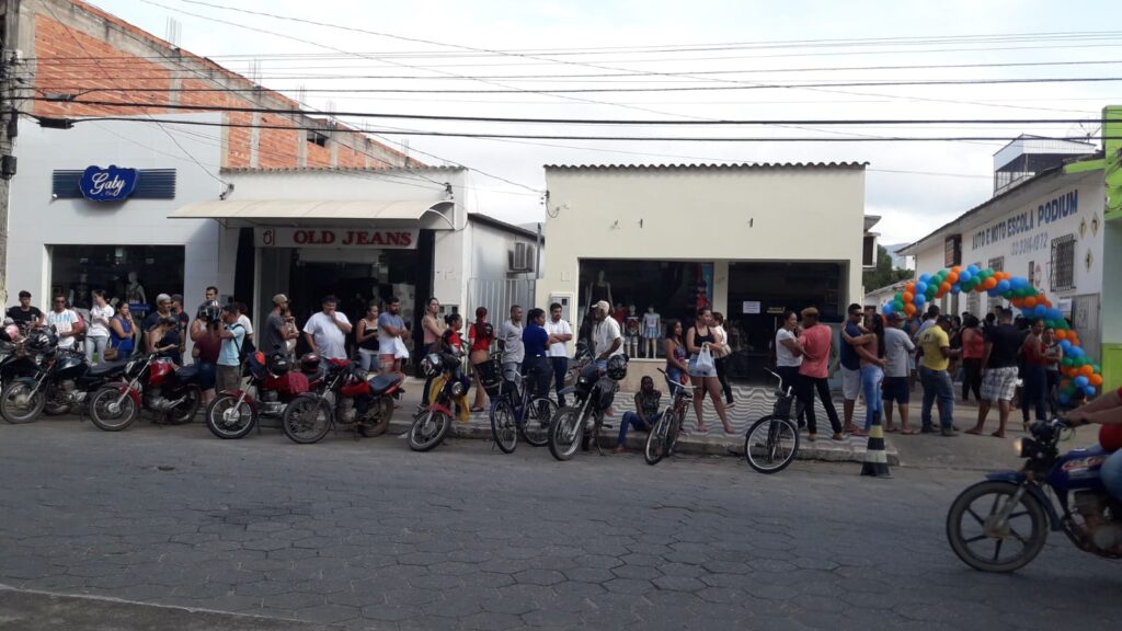Fila que se estende pela rua até o arco de balões coloridos na porta da autoescola